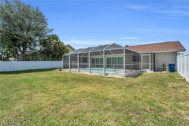 rear view of property featuring glass enclosure, a lawn, a fenced backyard, and a fenced in pool