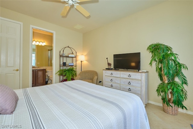 bedroom featuring ensuite bathroom, light colored carpet, and ceiling fan