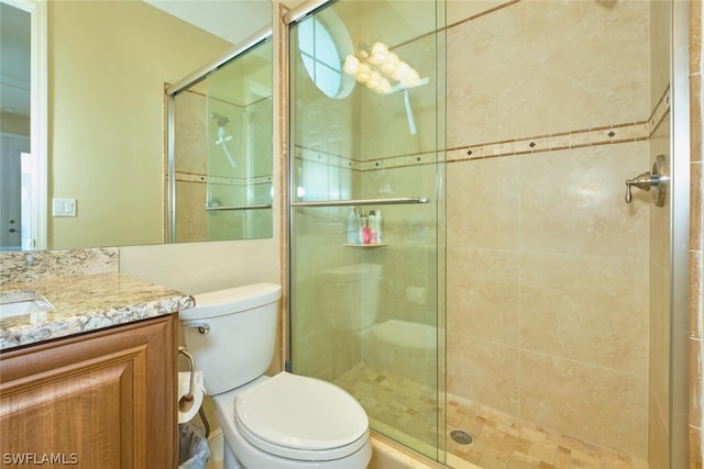 bathroom featuring toilet, an enclosed shower, and vanity