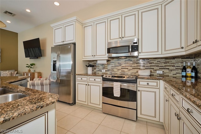 kitchen featuring light tile patterned flooring, dark stone countertops, backsplash, and appliances with stainless steel finishes