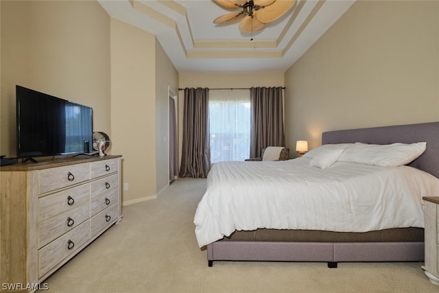 bedroom featuring a raised ceiling, ceiling fan, and light colored carpet