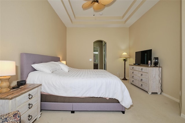 bedroom with a raised ceiling, ceiling fan, and light carpet