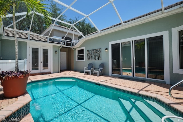 view of pool with french doors, glass enclosure, and a patio