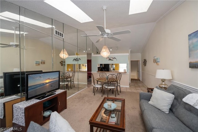 living room featuring vaulted ceiling with skylight, ceiling fan, and ornamental molding