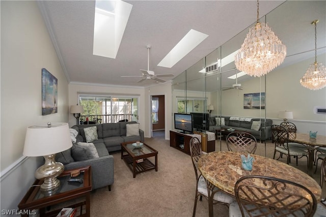 living room with carpet flooring, ceiling fan with notable chandelier, lofted ceiling with skylight, and ornamental molding