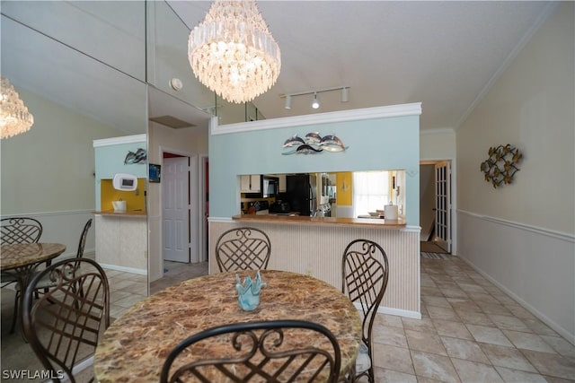 dining area with ornamental molding, vaulted ceiling, and a notable chandelier