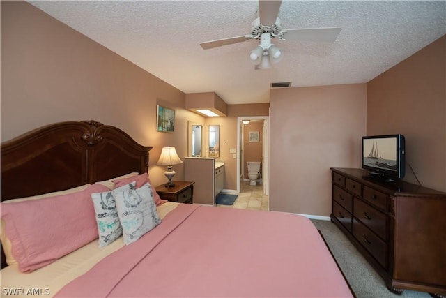 bedroom featuring a textured ceiling, ensuite bathroom, and ceiling fan