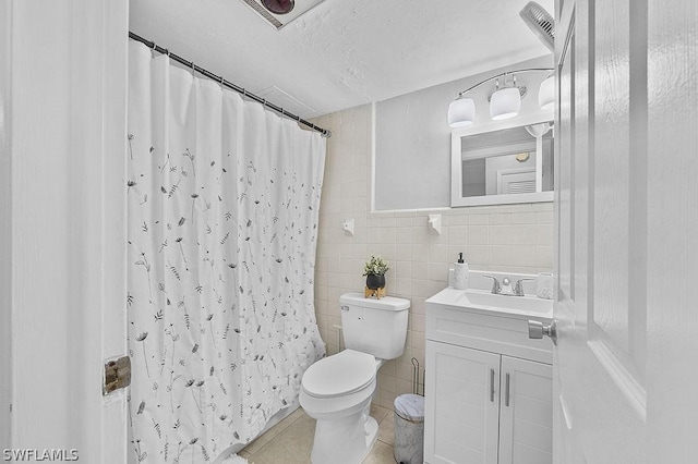 bathroom with a shower with curtain, a textured ceiling, toilet, vanity, and tile walls