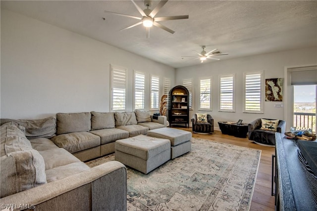 living room featuring hardwood / wood-style floors, plenty of natural light, ceiling fan, and a textured ceiling