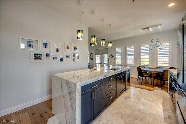 kitchen featuring french doors, a center island with sink, light stone counters, track lighting, and sink