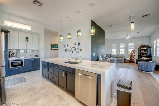 kitchen with white cabinetry, stainless steel appliances, a kitchen island with sink, sink, and ceiling fan