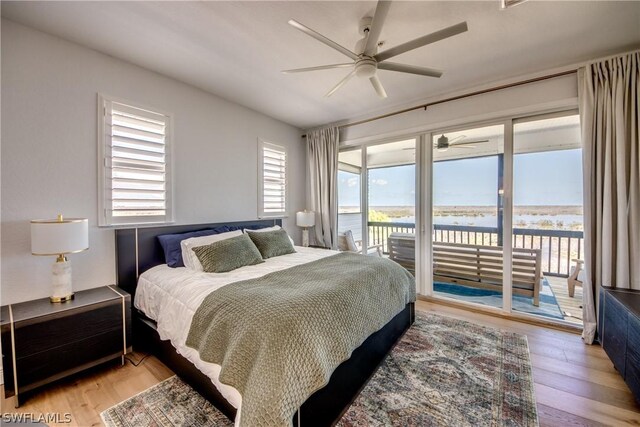 bedroom with ceiling fan, light hardwood / wood-style floors, access to outside, and a water view