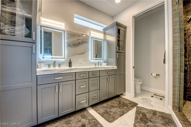 bathroom featuring walk in shower, tile flooring, double sink, vanity with extensive cabinet space, and toilet