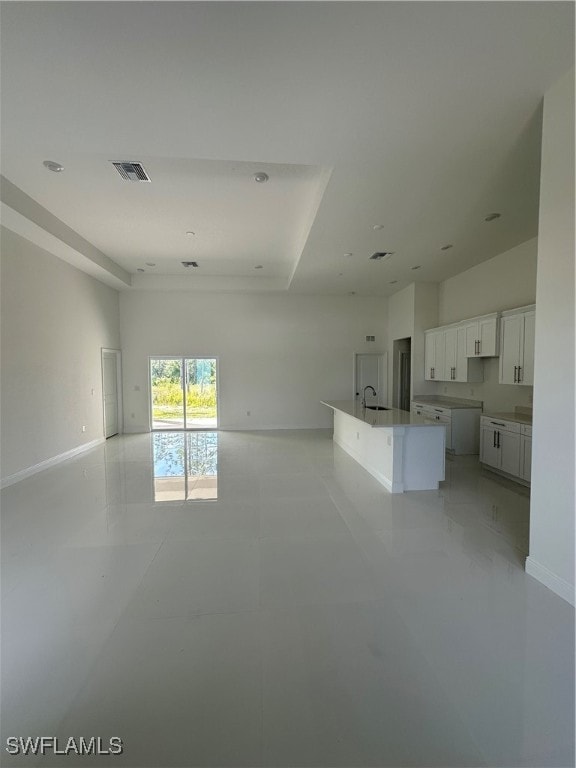 interior space with a center island with sink, white cabinets, and sink