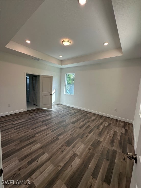 unfurnished room with dark hardwood / wood-style flooring and a tray ceiling