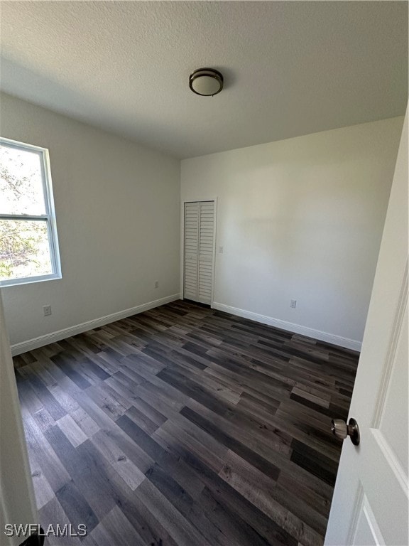 empty room featuring dark hardwood / wood-style flooring and a textured ceiling