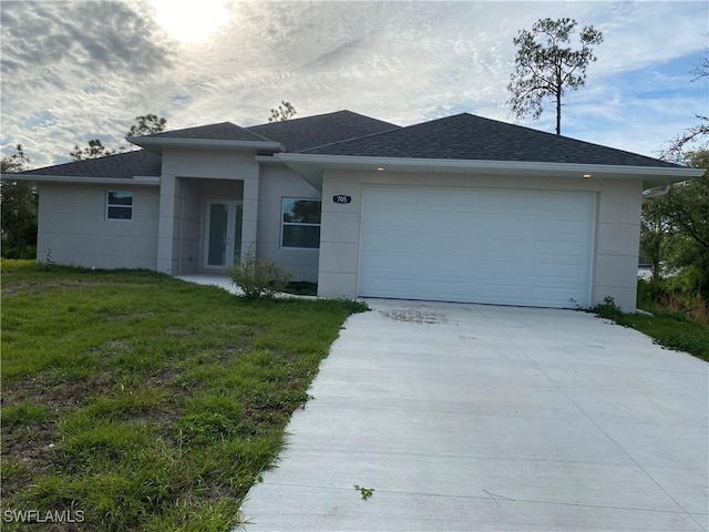 view of front of home with a garage, concrete driveway, french doors, roof with shingles, and a front yard