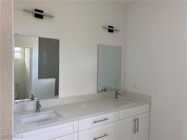 bathroom featuring double vanity, a sink, and toilet