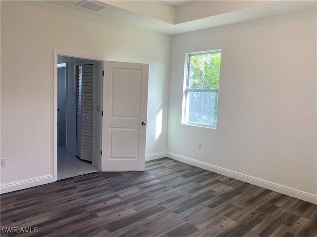 unfurnished room featuring visible vents, baseboards, and dark wood-type flooring