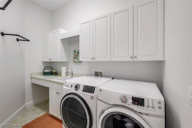 clothes washing area with cabinet space, baseboards, separate washer and dryer, and a sink