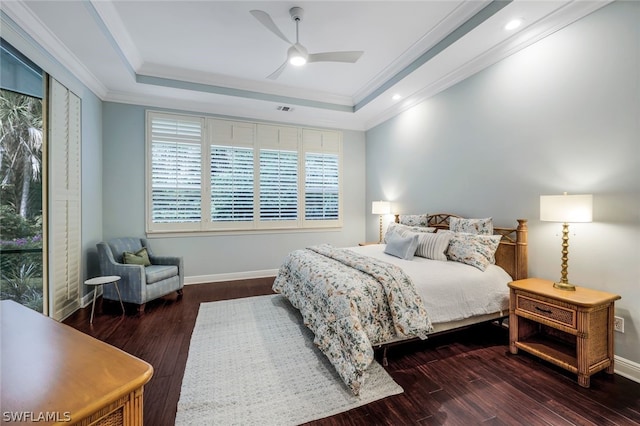 bedroom with baseboards, a tray ceiling, dark wood finished floors, and crown molding