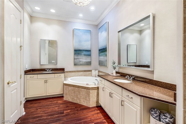 full bath with crown molding, a garden tub, a sink, and wood finished floors