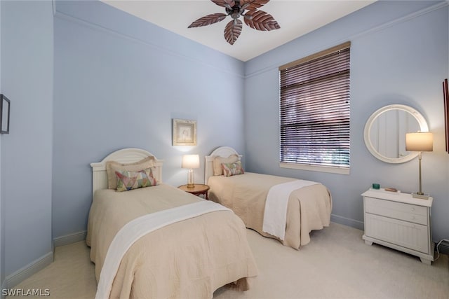 bedroom featuring light carpet, a ceiling fan, and baseboards