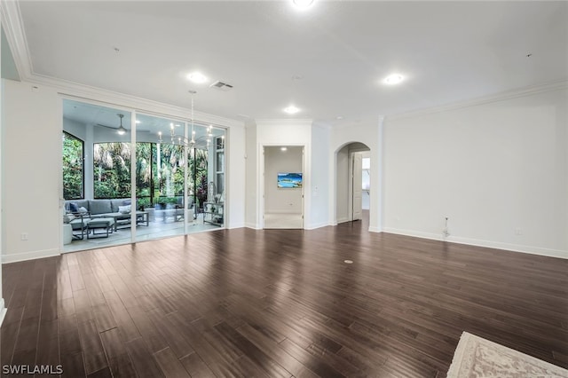 unfurnished living room with visible vents, arched walkways, dark wood finished floors, baseboards, and ornamental molding