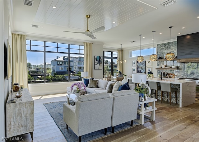 living room with sink, light wood-type flooring, and ceiling fan