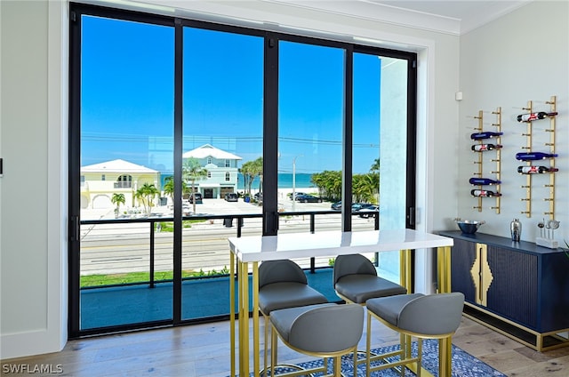 dining space featuring a wealth of natural light, ornamental molding, and wood-type flooring