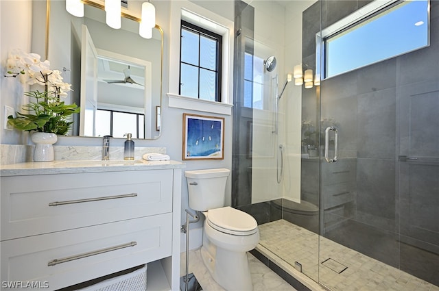 bathroom featuring vanity with extensive cabinet space, ceiling fan, toilet, tile floors, and a shower with shower door