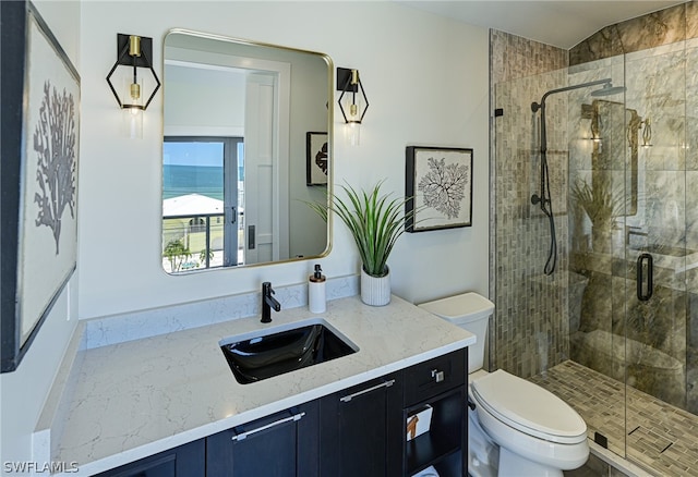 bathroom featuring a shower with shower door, toilet, and vanity