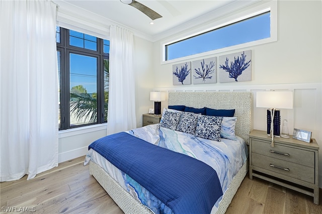 bedroom with ornamental molding, wood-type flooring, and ceiling fan