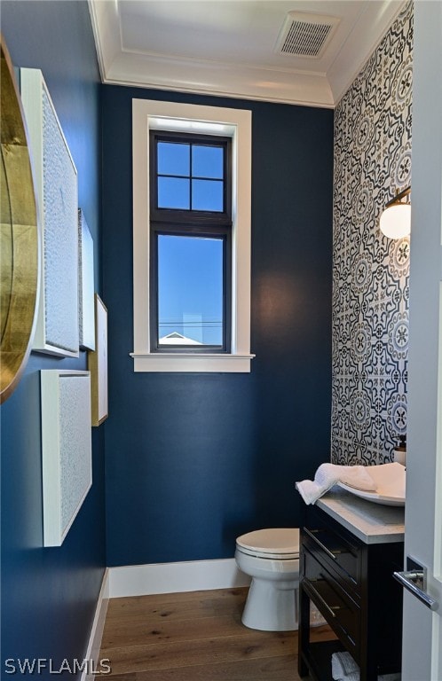 bathroom with hardwood / wood-style flooring, ornamental molding, vanity, and toilet