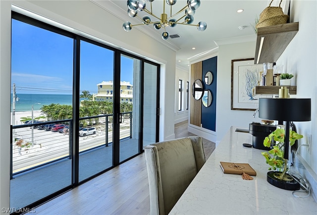 dining space featuring a water view, ornamental molding, a chandelier, and light wood-type flooring