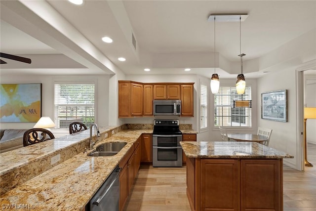 kitchen featuring a tray ceiling, hanging light fixtures, sink, and stainless steel appliances