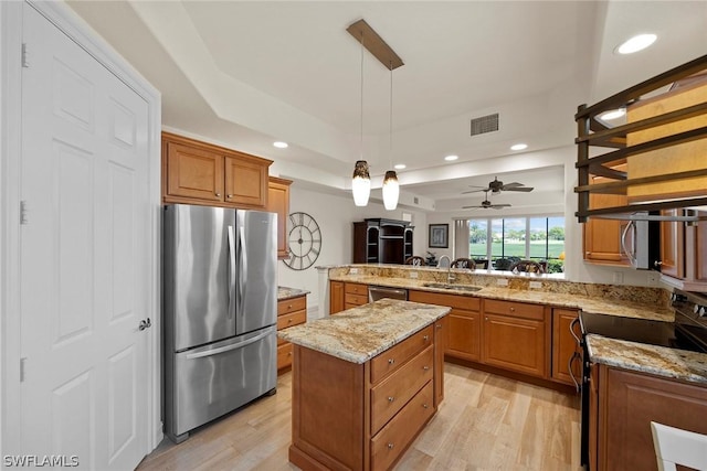 kitchen featuring appliances with stainless steel finishes, ceiling fan, sink, decorative light fixtures, and a kitchen island