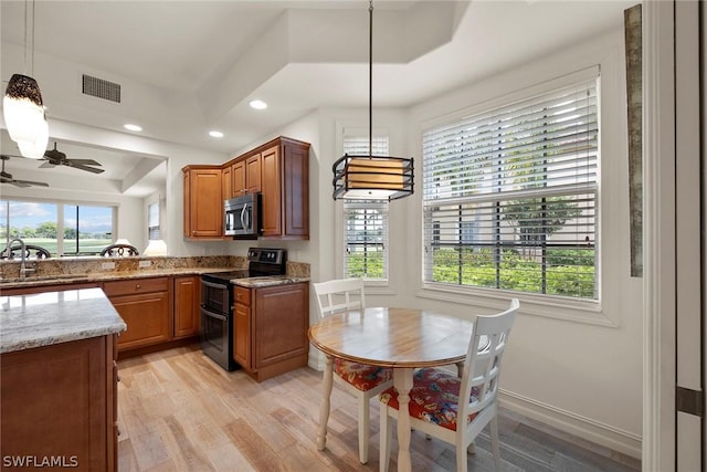 kitchen featuring sink, black / electric stove, decorative light fixtures, light hardwood / wood-style floors, and light stone counters