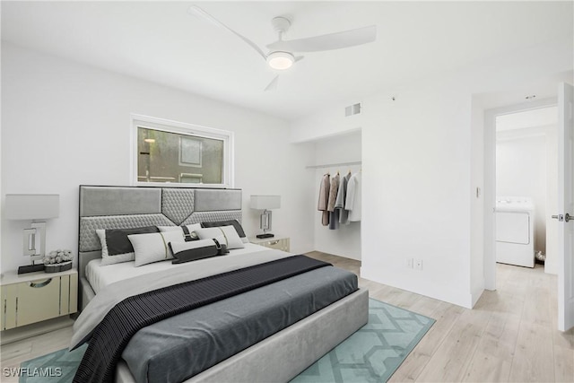 bedroom featuring ceiling fan, a closet, light wood-type flooring, and washer / dryer