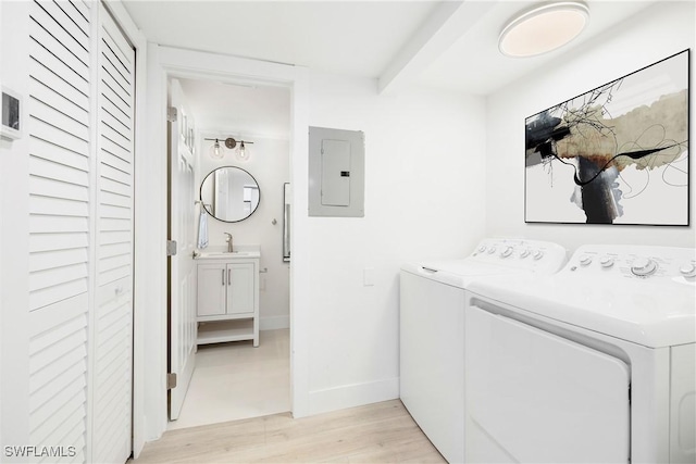 laundry room featuring sink, light wood-type flooring, independent washer and dryer, and electric panel