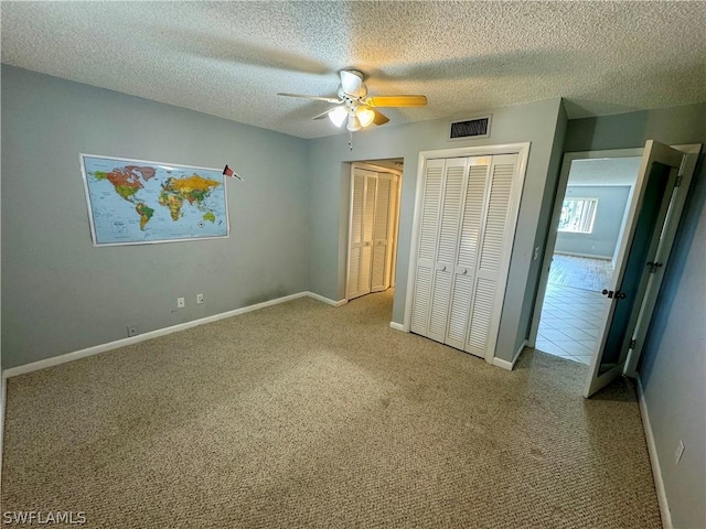 unfurnished bedroom featuring light colored carpet, ceiling fan, and a textured ceiling