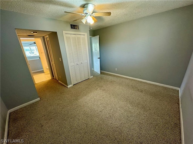 unfurnished bedroom with a closet, a textured ceiling, ceiling fan, and light carpet