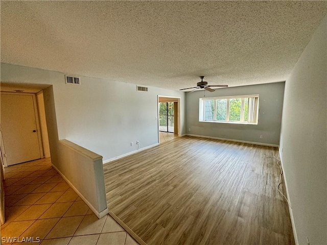 unfurnished room with a textured ceiling, ceiling fan, and light wood-type flooring