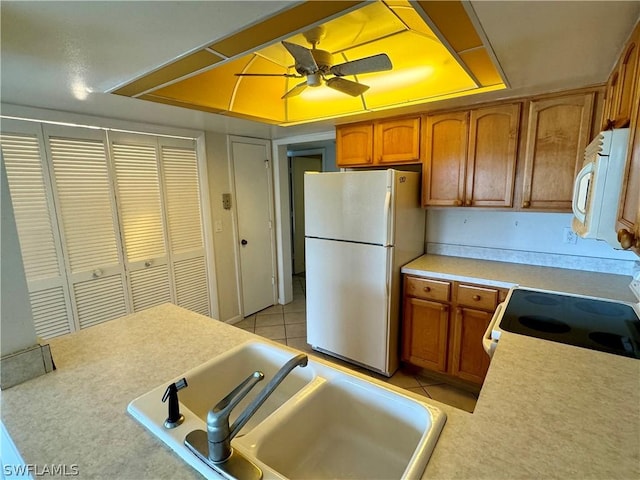 kitchen featuring sink, white appliances, ceiling fan, light tile patterned floors, and a tray ceiling