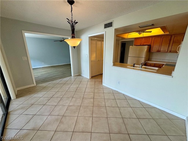 interior space featuring sink, ceiling fan, a textured ceiling, and light tile patterned floors