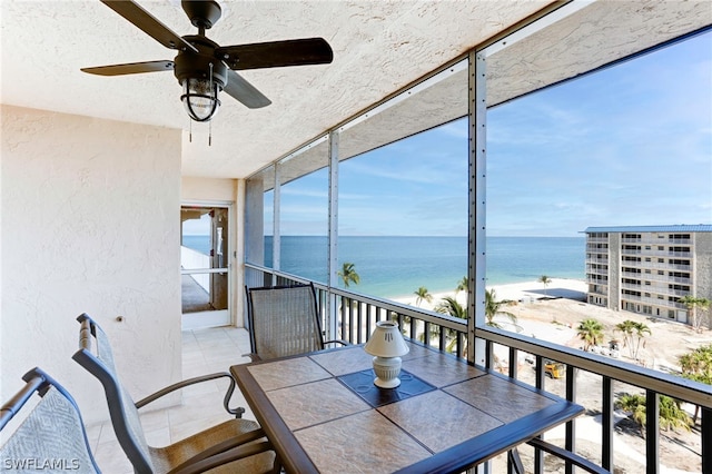 sunroom / solarium featuring a water view and ceiling fan