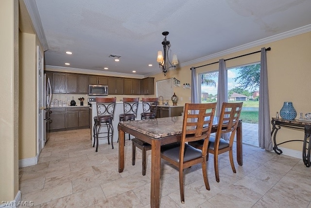 dining area featuring an inviting chandelier, sink, and crown molding