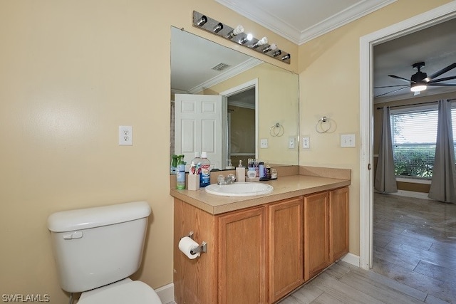 bathroom with crown molding, hardwood / wood-style flooring, ceiling fan, vanity, and toilet