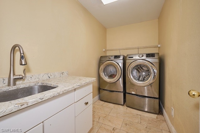 clothes washing area featuring separate washer and dryer, sink, and cabinets