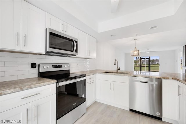 kitchen with stainless steel appliances, sink, white cabinets, and light stone counters